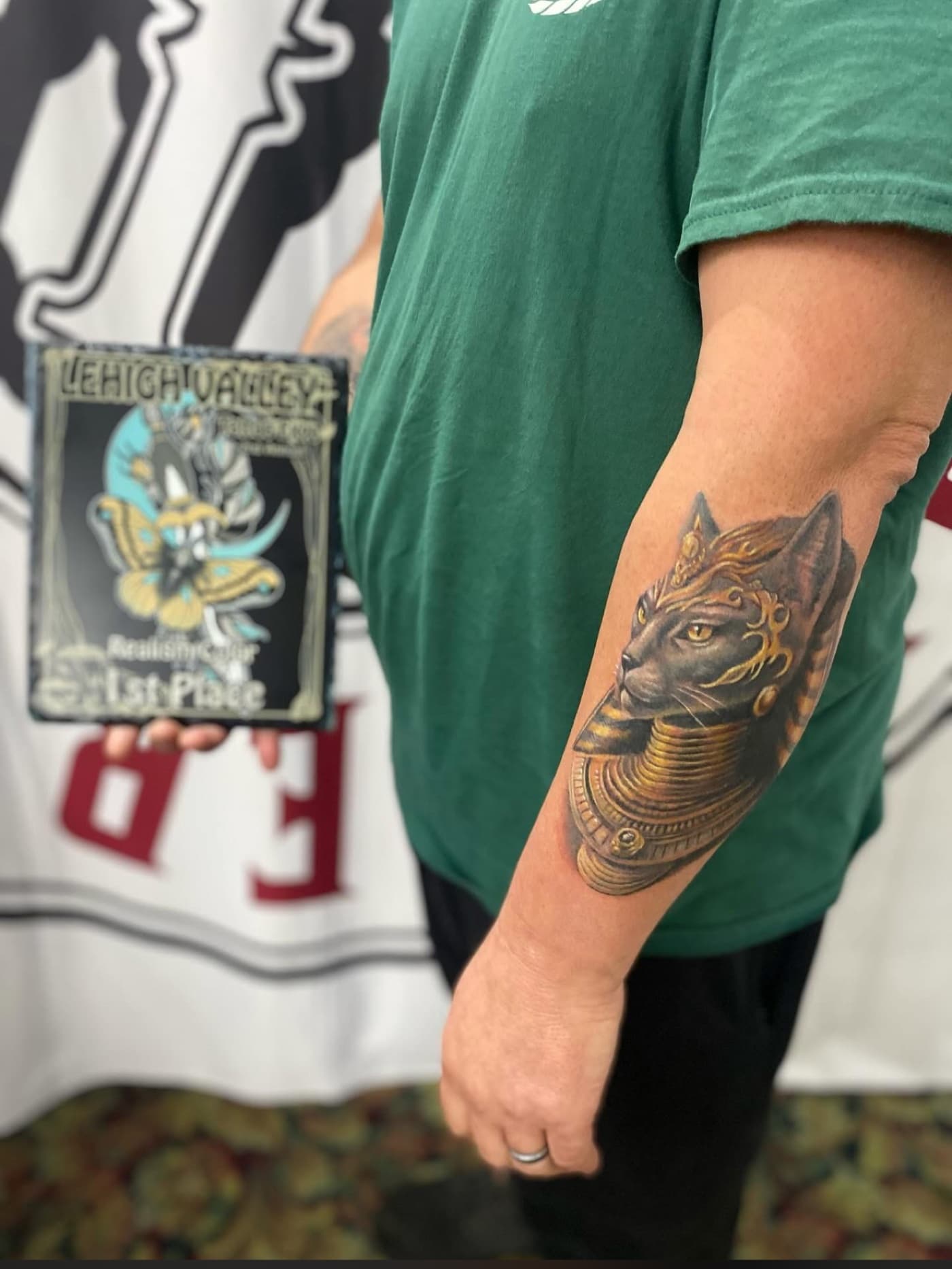 Award plaque next to a healed black and grey cat tattoo by Fodor Ink